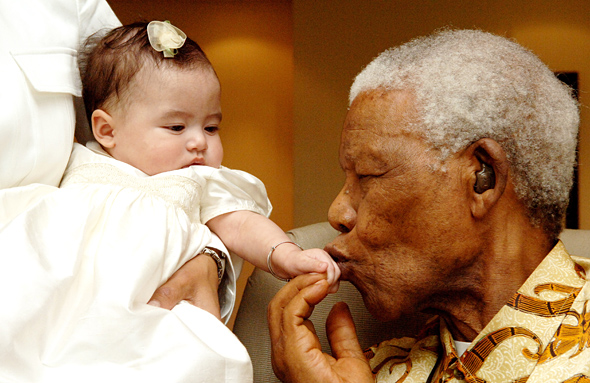M. Mandela embrasse un bébé sur la main. © Photo NMF/Peter Morey