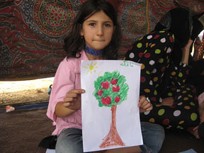 girl holding up her drawing of a tree