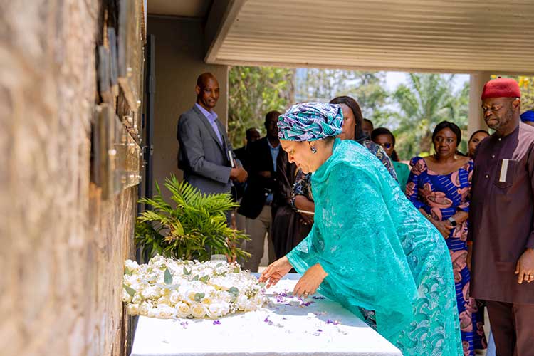 Amina Mohammed leans over a table that has a flower arrangement