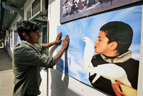 Un joven afgano pone un póster para el Día Internacional de la Paz