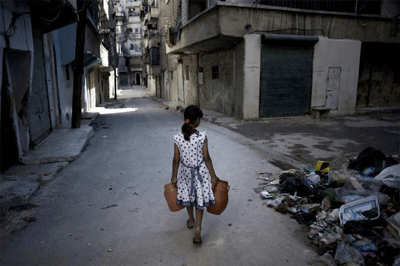 A girl carrying jerrycans of water, walks past a pile of debris on a street in Aleppo, Syria. UNICEF/NYHQ2012-1293/Romenzi