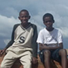 Two boys sit on the broken wall surrounding the orphanage.