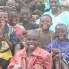 A portrait of Godelieve sitting with children. Godelieve counsels widows and orphans in Rwanda.