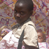 A young girl carries her sister on her back.