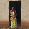 A woman that is counseled by Godelieve stands in front of her new home.