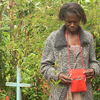 Godelieve stands between two graves. She lost her two daughters and husband in the 1994 genocide.