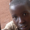 A young child looks into a window from outside.
