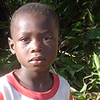 A little boy sits among the crops in his father’s garden.