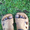 A young boy’s feet on the grass.