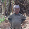A little boy stands beside a baby goat.