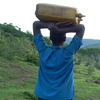 A young woman carries a jug of water home.
