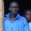 Two men stand in front of their home.